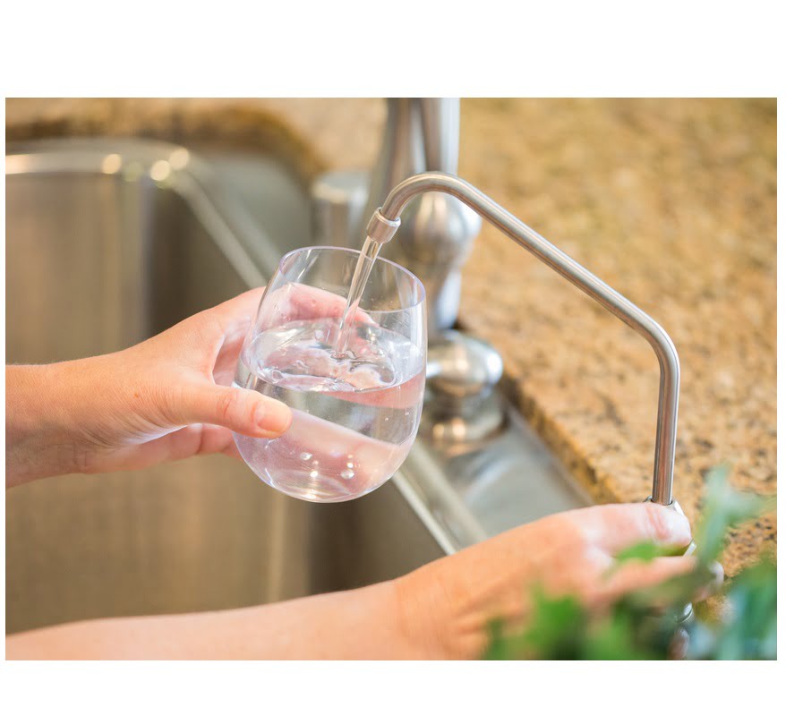 Φίλτρα Νερού. Γυναίκα που ρίχνει φρέσκο ​​καθαρό νερό από βρυσάκι για φίλτρο νερού σε ποτήρι στην κουζίνα.
